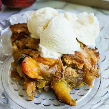peach cobbler made with cake mix, on plate with a scoop of vanilla ice cream.