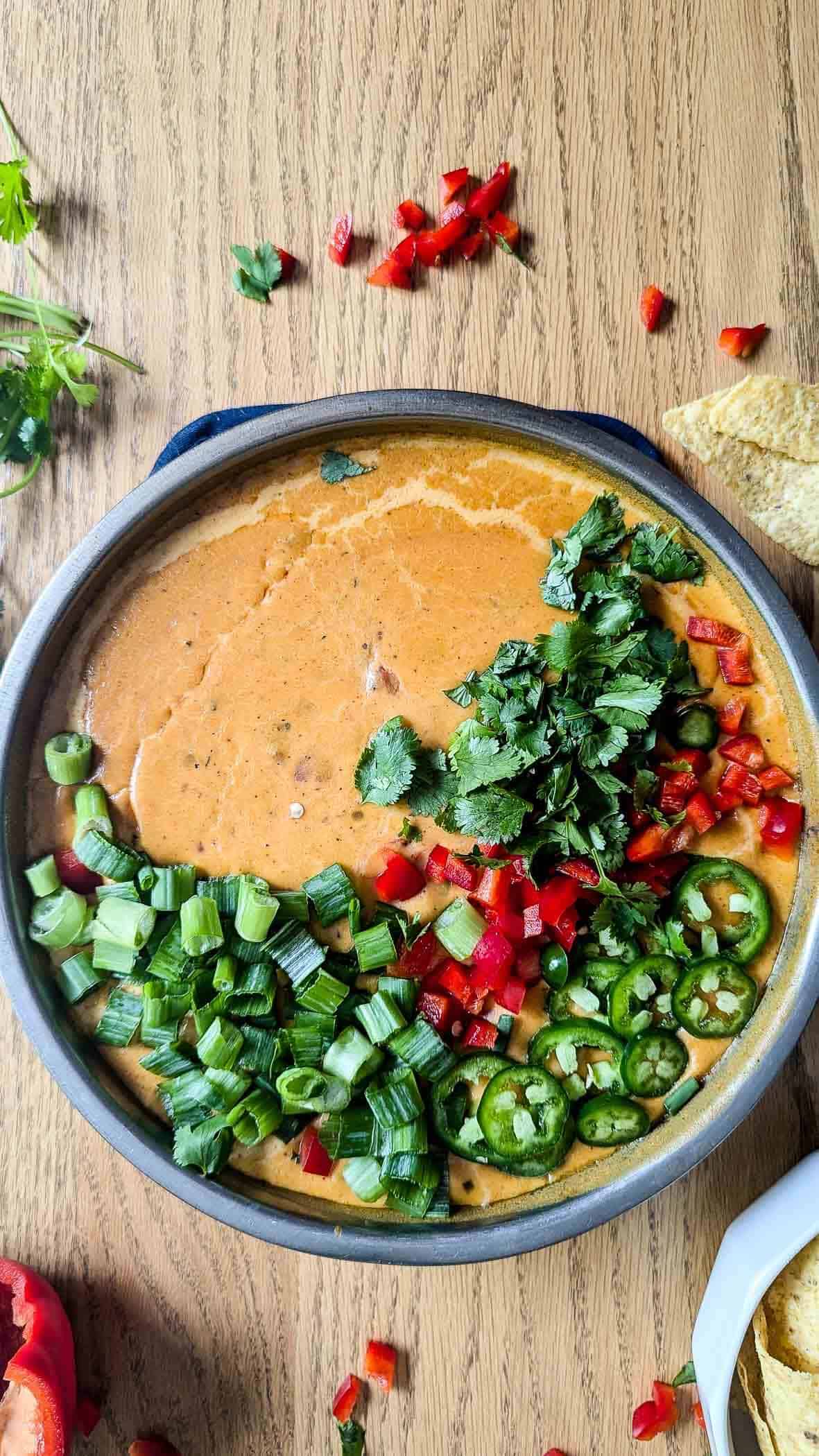 smoked queso dip with garnishes on the top and chips on the side.