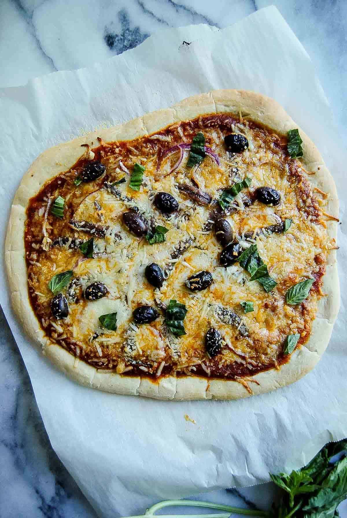 baked anchovy pizza on cutting board.