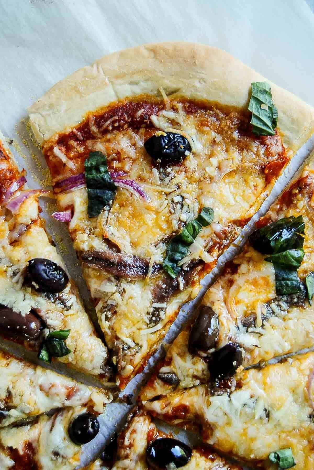 slice of anchovy pizza on parchment paper.