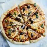 sliced anchovy pizza with kalamata olives, red onion, garlic and fresh basil.