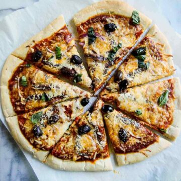 sliced anchovy pizza with kalamata olives, red onion, garlic and fresh basil.