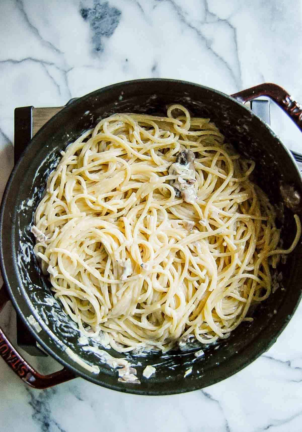 spaghetti noodles with creamy truffle sauce in pot on countertop.