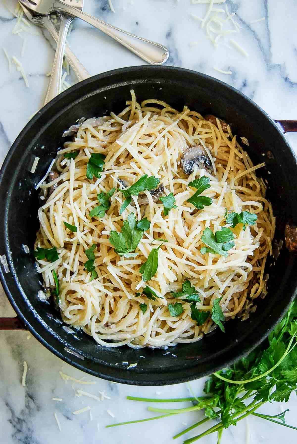 truffle pasta in staub pot on countertop with parsley on the side.