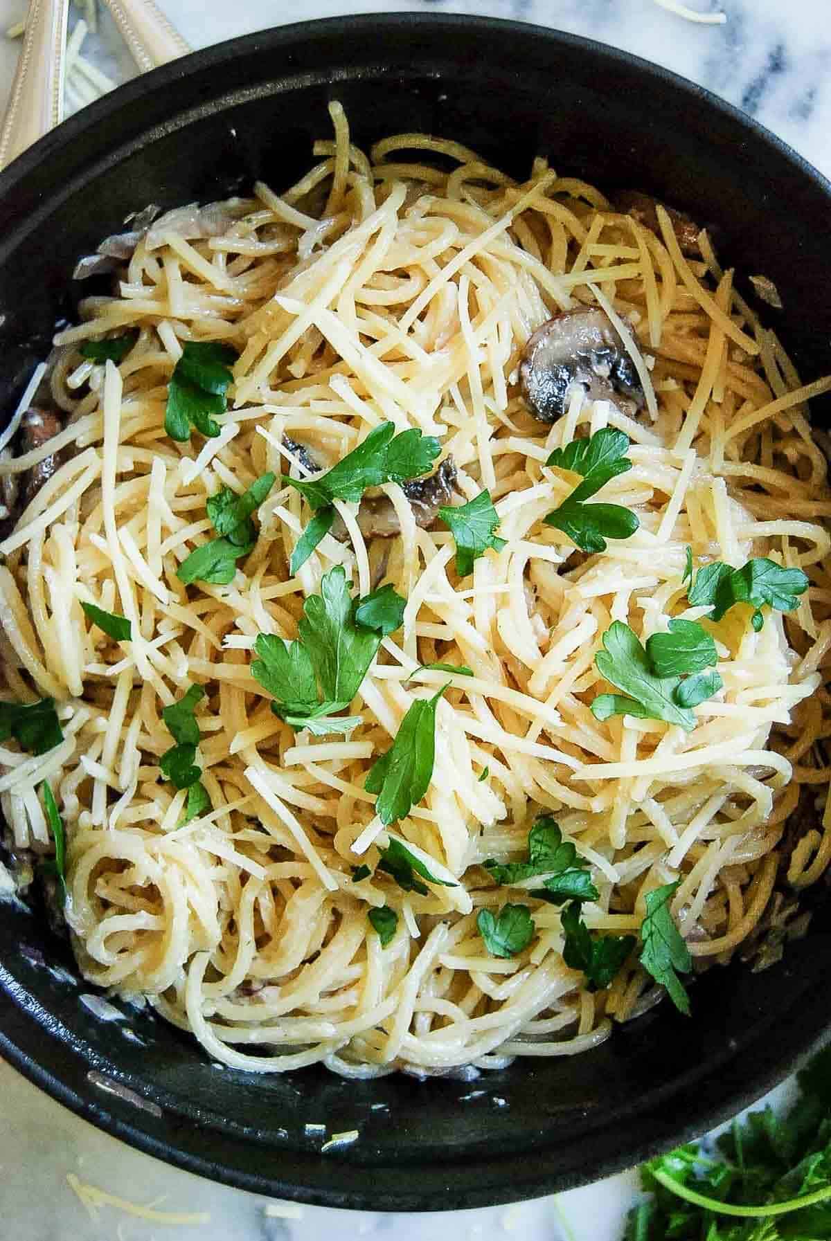 closeup of creamy black truffle pasta, garnished with parsley.