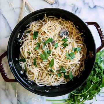 creamy black truffle pasta in pot with parsley on the side.