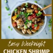 chicken shrimp and veggie stir fry in bowl with chopsticks sticking out of the side.