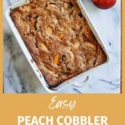 peach cobbler in baking dish on countertop with peaches on the side.