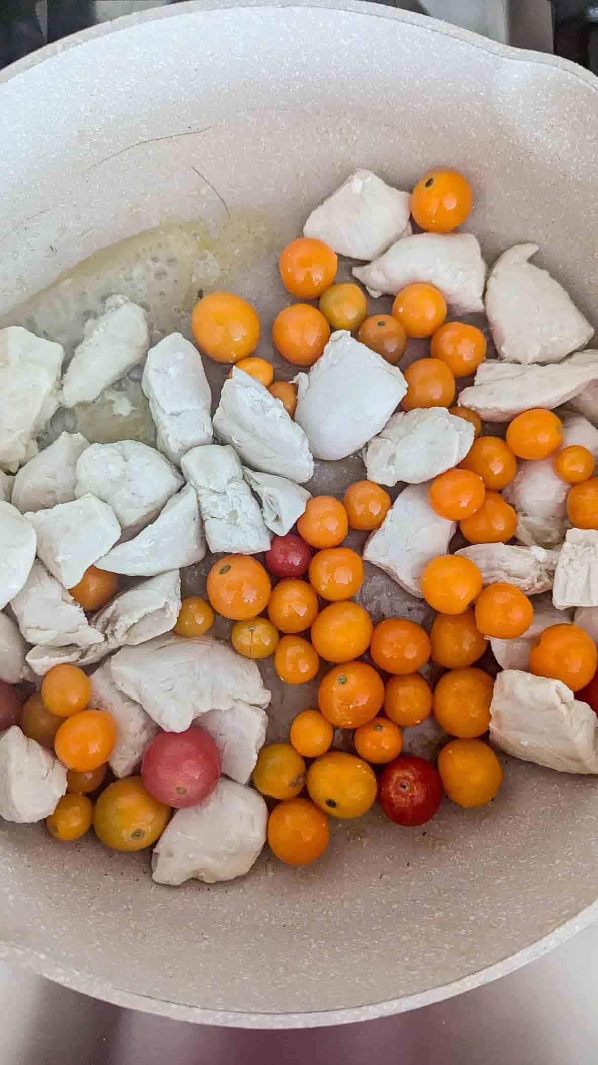 chicken and cherry tomatoes in pan on stovetop.