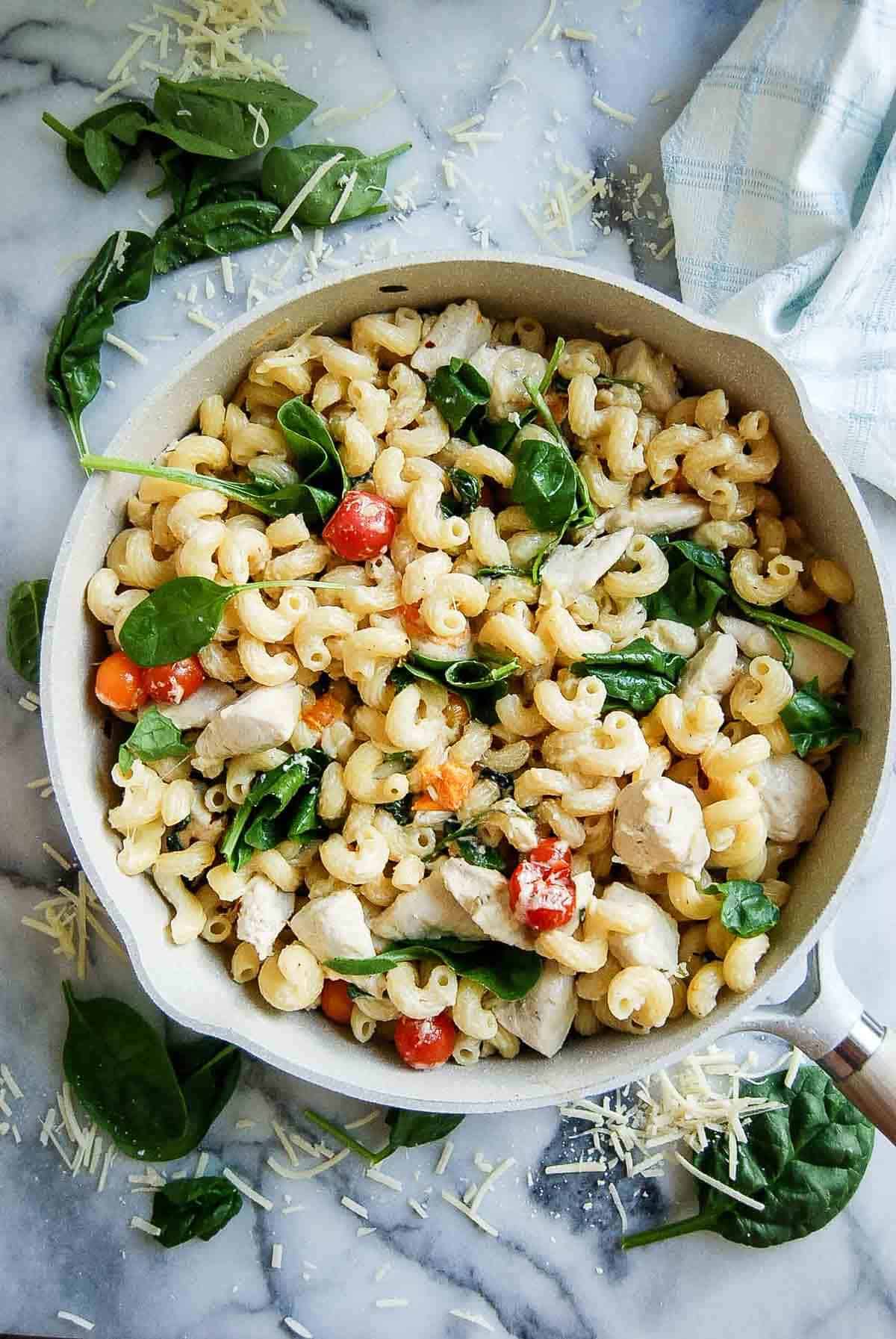 pot of Boursin cheese pasta with chicken and tomatoes on countertop.