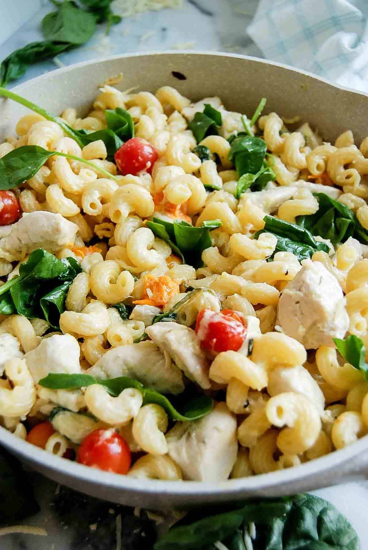 pot of Boursin cheese pasta with chicken and tomatoes on countertop - side view.