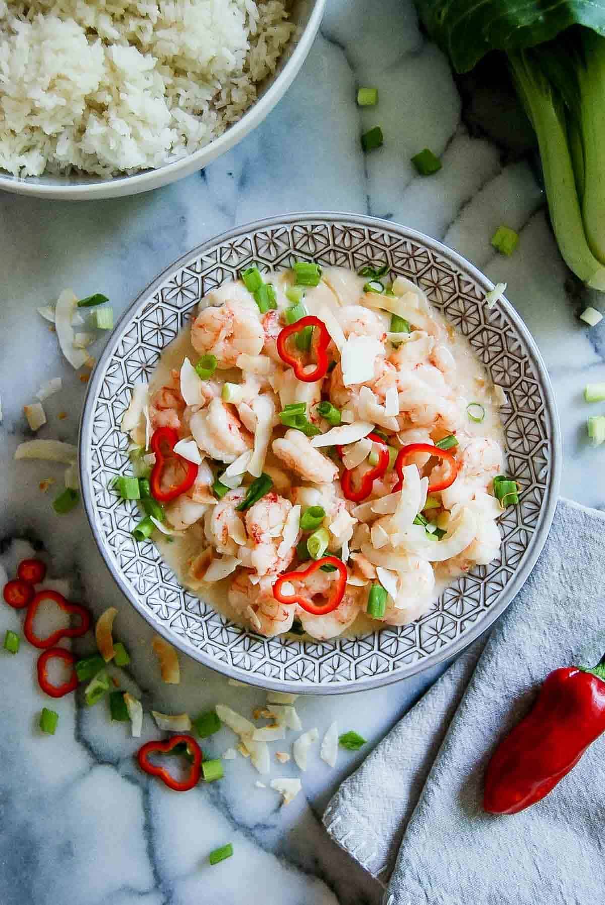 Chinese coconut shrimp in bowl on countertop with rice and bok choy on the side.