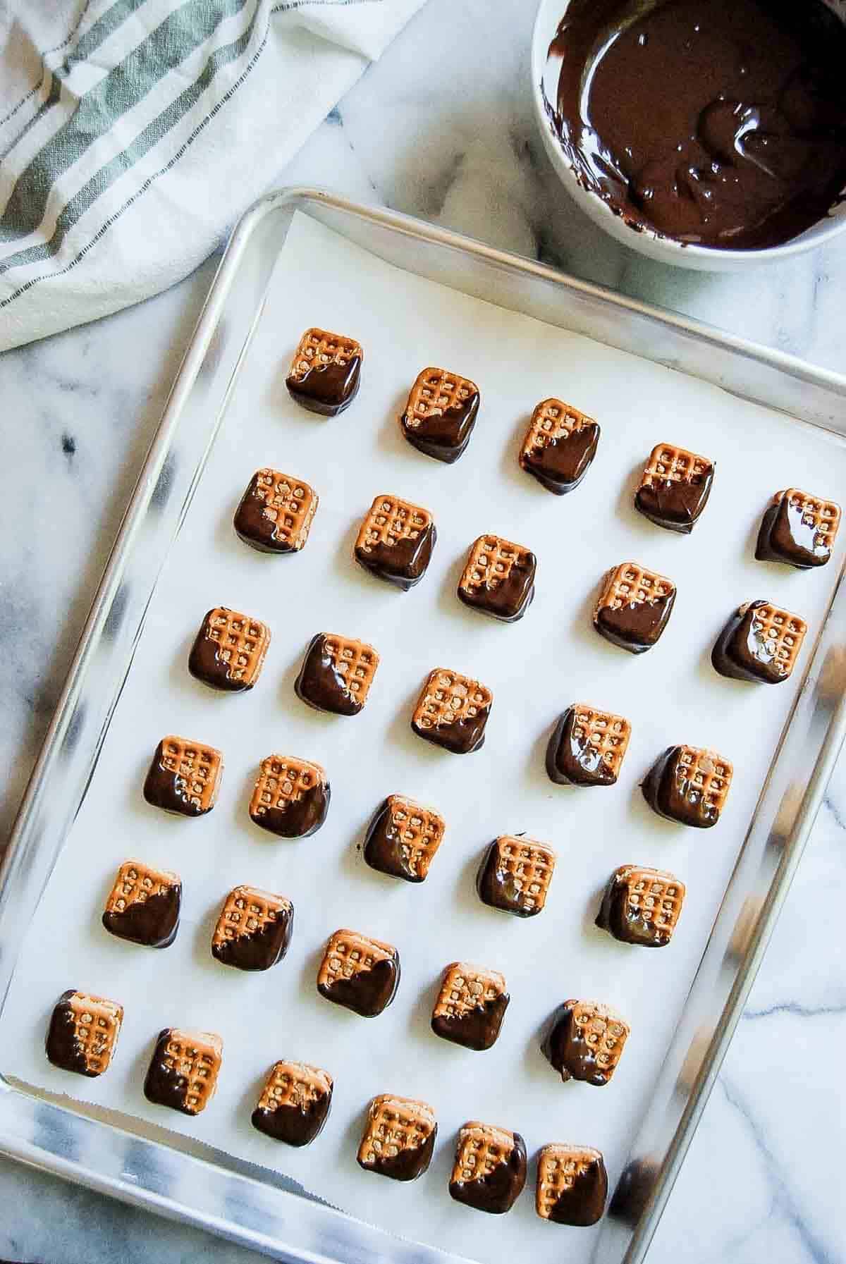 chocolate dipped peanut butter pretzel bites on baking sheet.