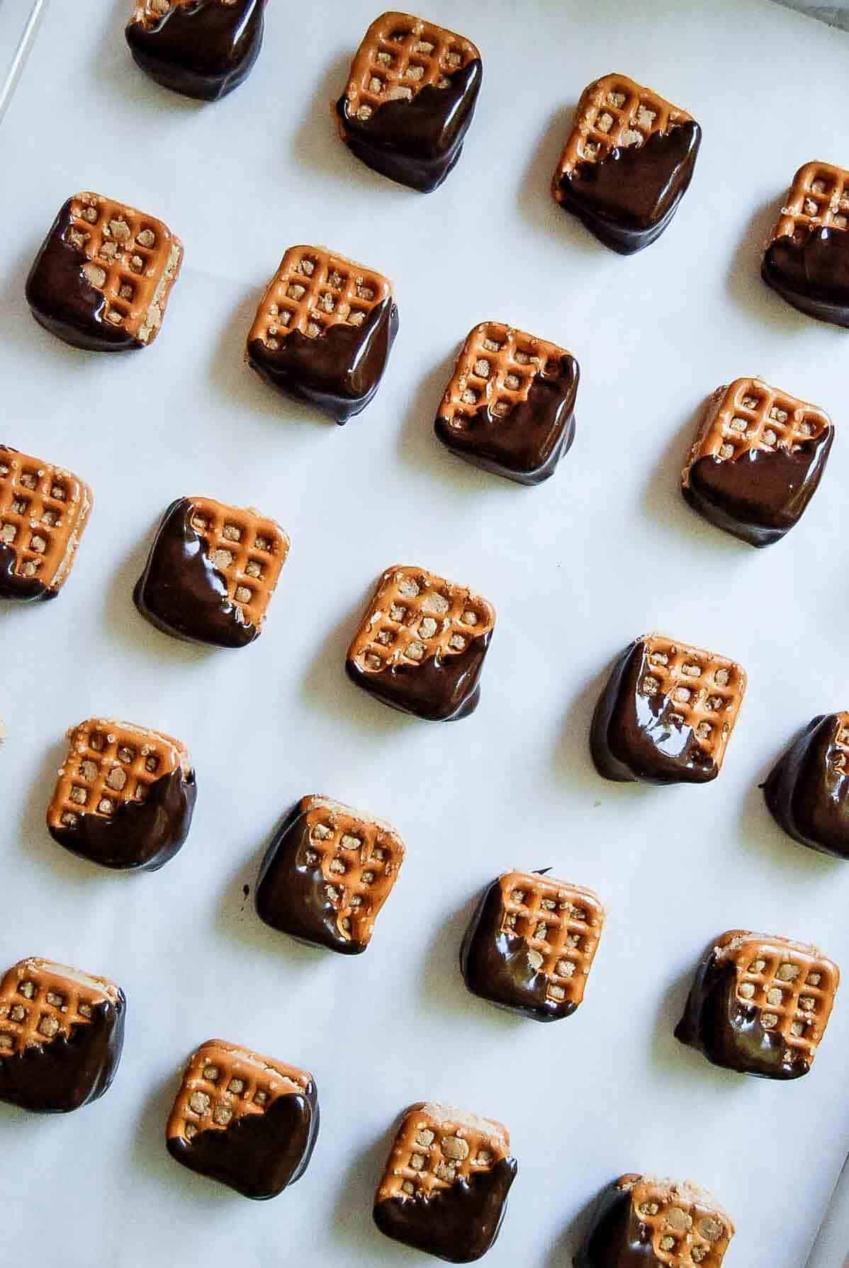 chocolate covered peanut butter pretzel bites on parchment lined baking tray.