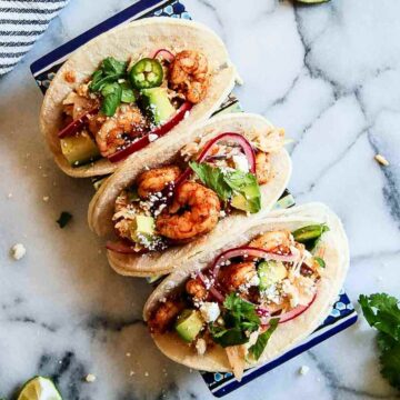 3 baja shrimp tacos on tray with lime on the side.