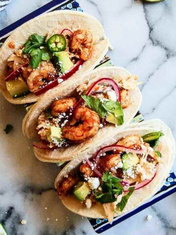 3 baja shrimp tacos on tray with lime on the side.