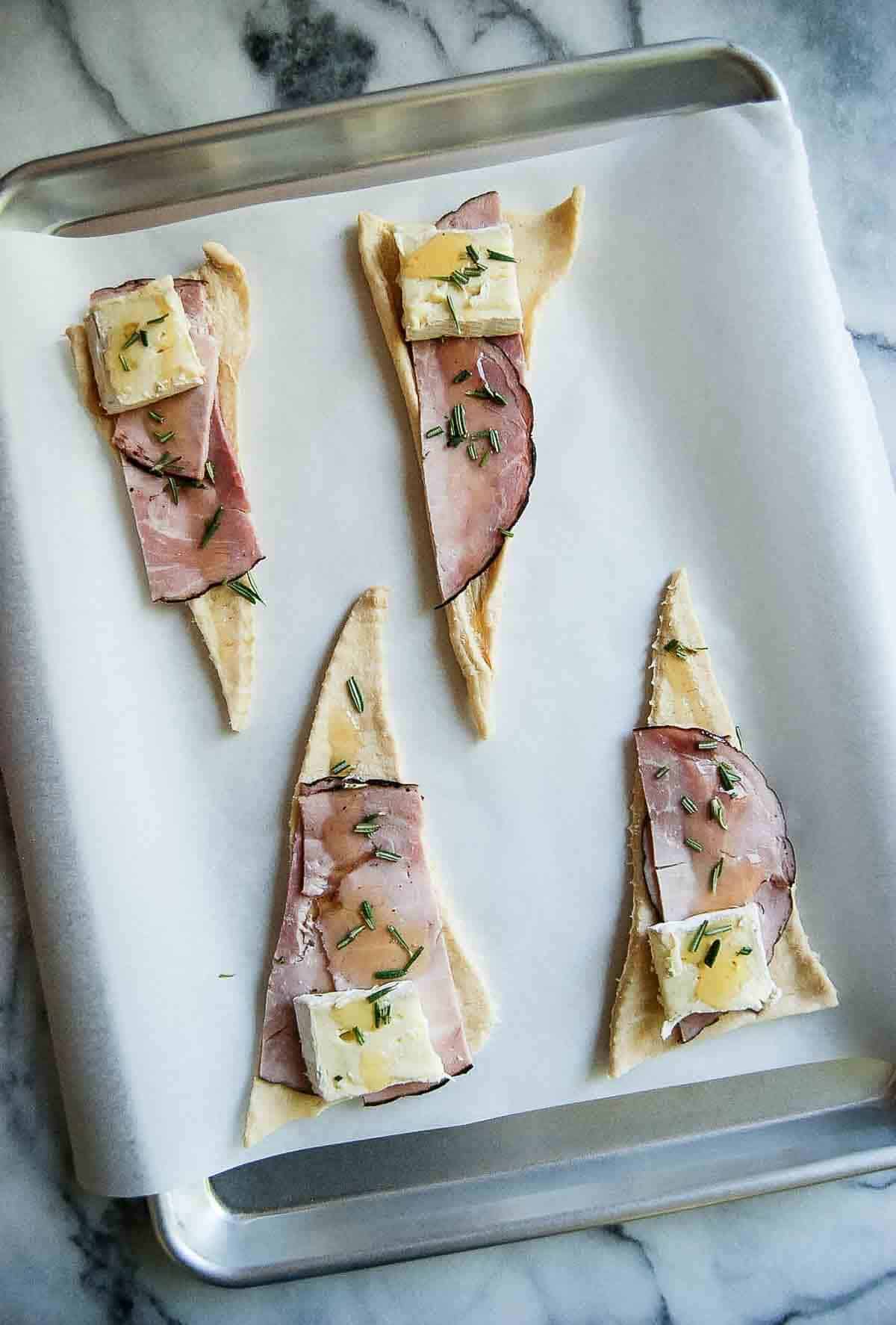 rolled out crescent roll dough with ham and cheese, honey and rosemary.