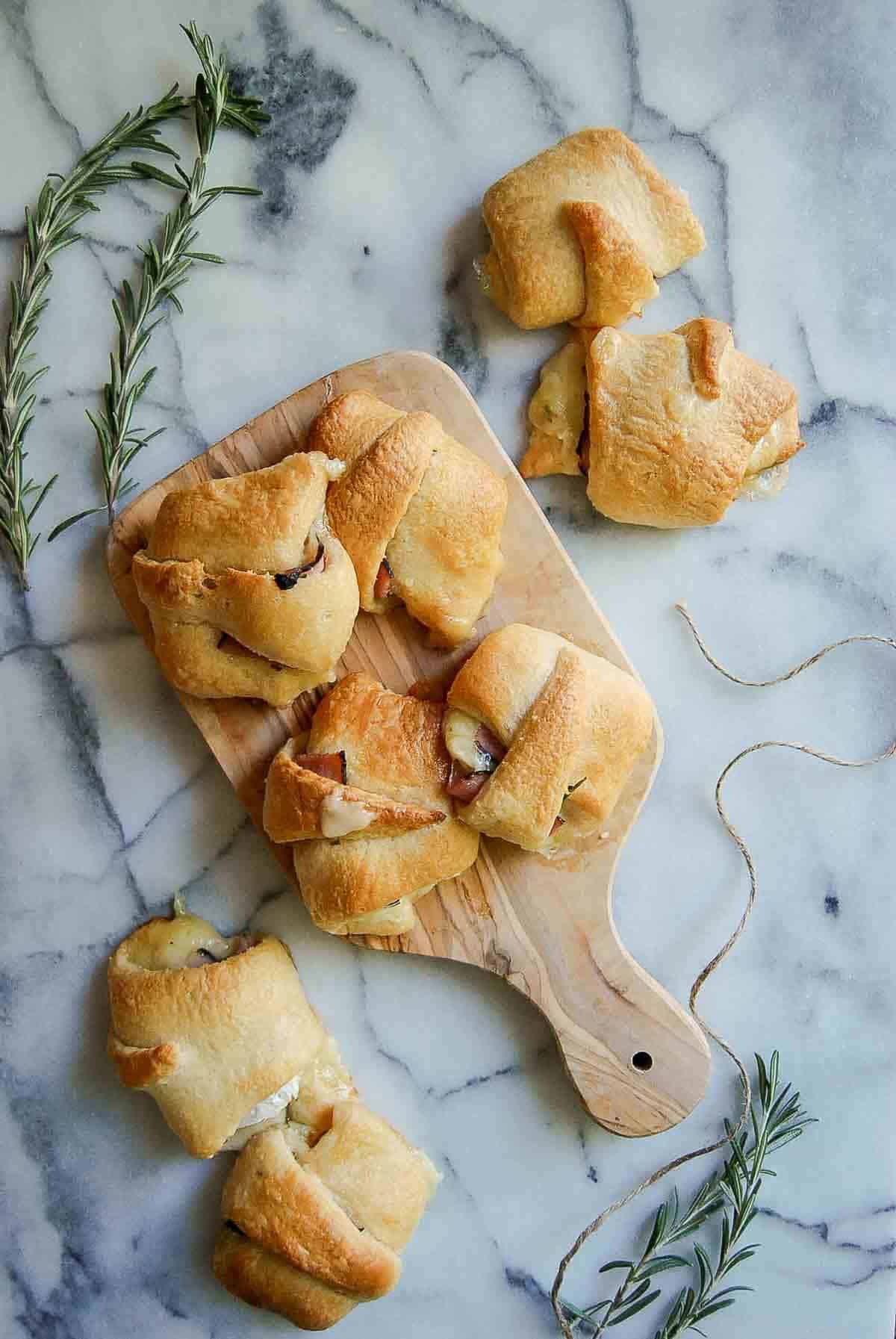 baked ham and cheese crescent rolls on countertop with fresh rosemary on the side.