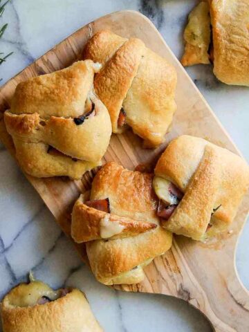 baked ham and cheese crescent roll sandwiches on cutting board.