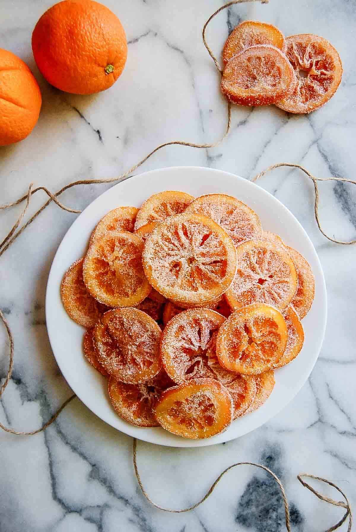 candied oranges on plate with whole oranges on the side.