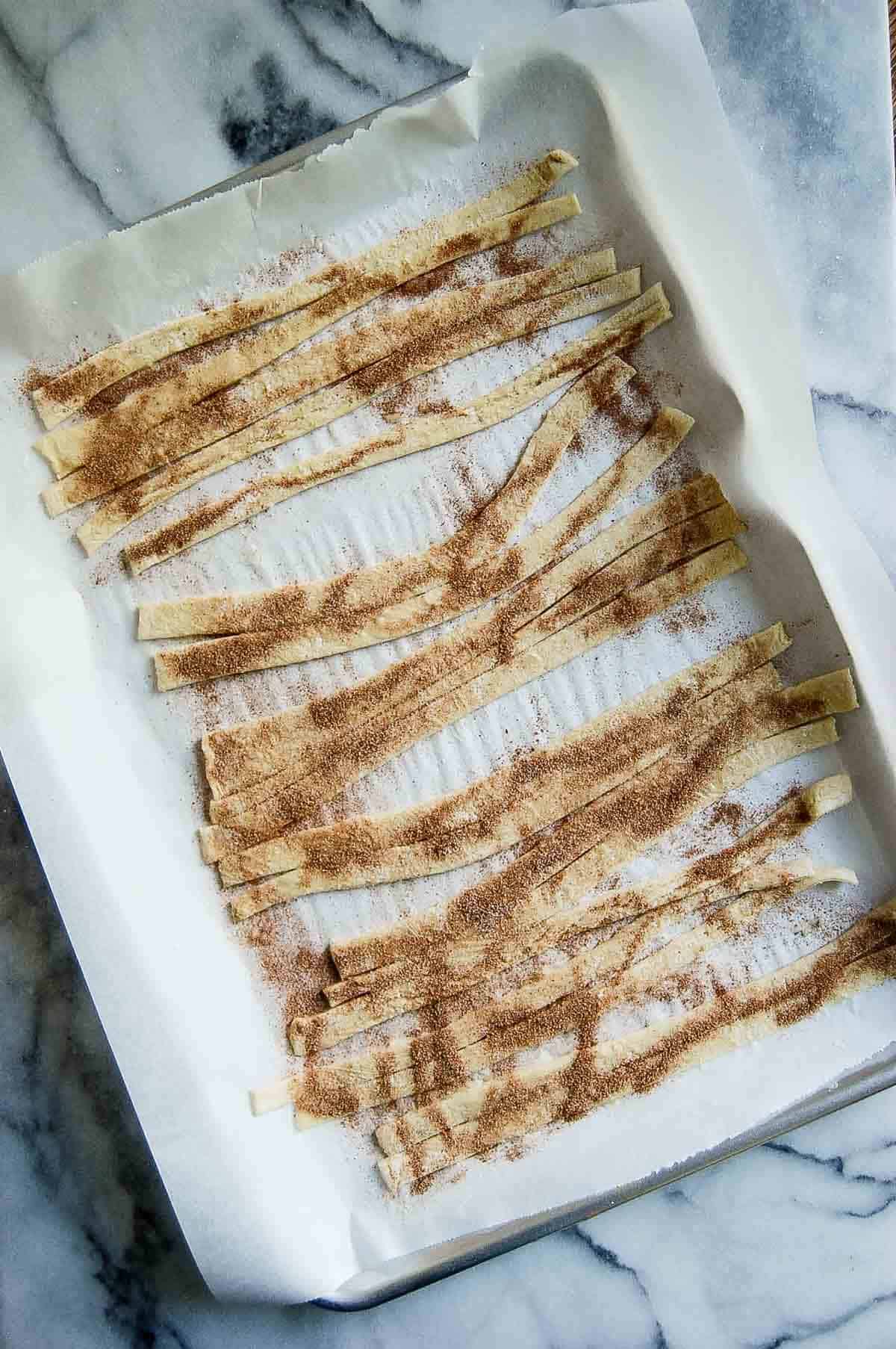 strips of puff pastry on baking sheet brushed with butter and sprinkled with cinnamon sugar.