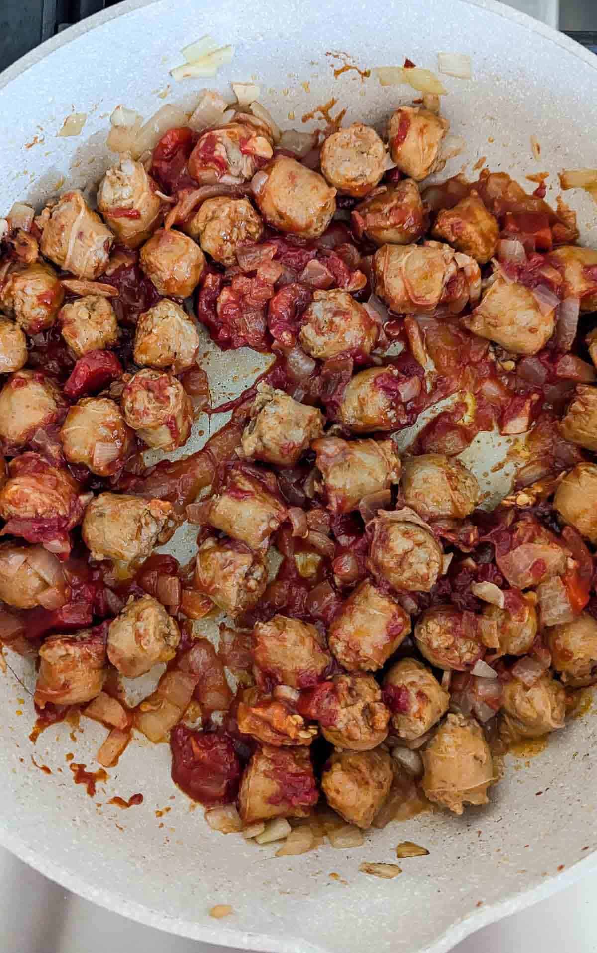 sausage, onions, calibrian peppers, and tomato paste cooking in pot.