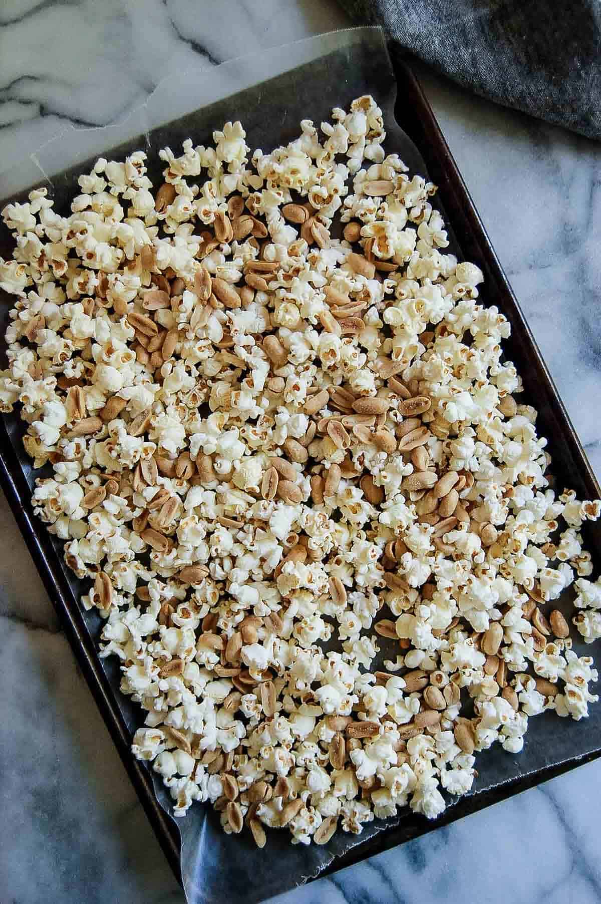 popcorn and peanuts on sheet pan lined with wax paper.