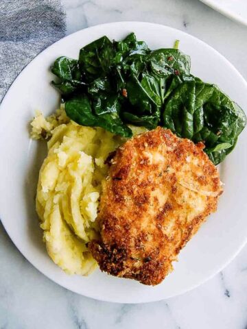 crispy chicken fritta on plate with mashed potatoes and cooked spinach.