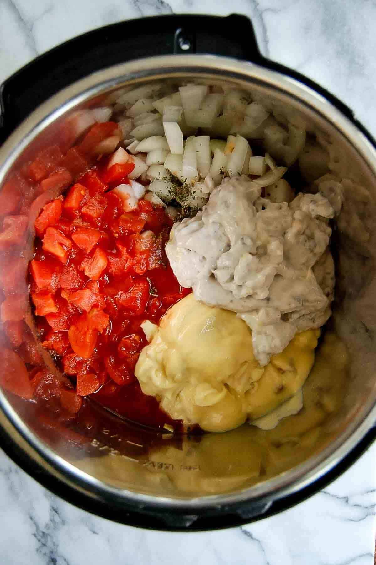 crockpot with chicken, tomatoes, cream of mushroom, cream of chicken and onions.