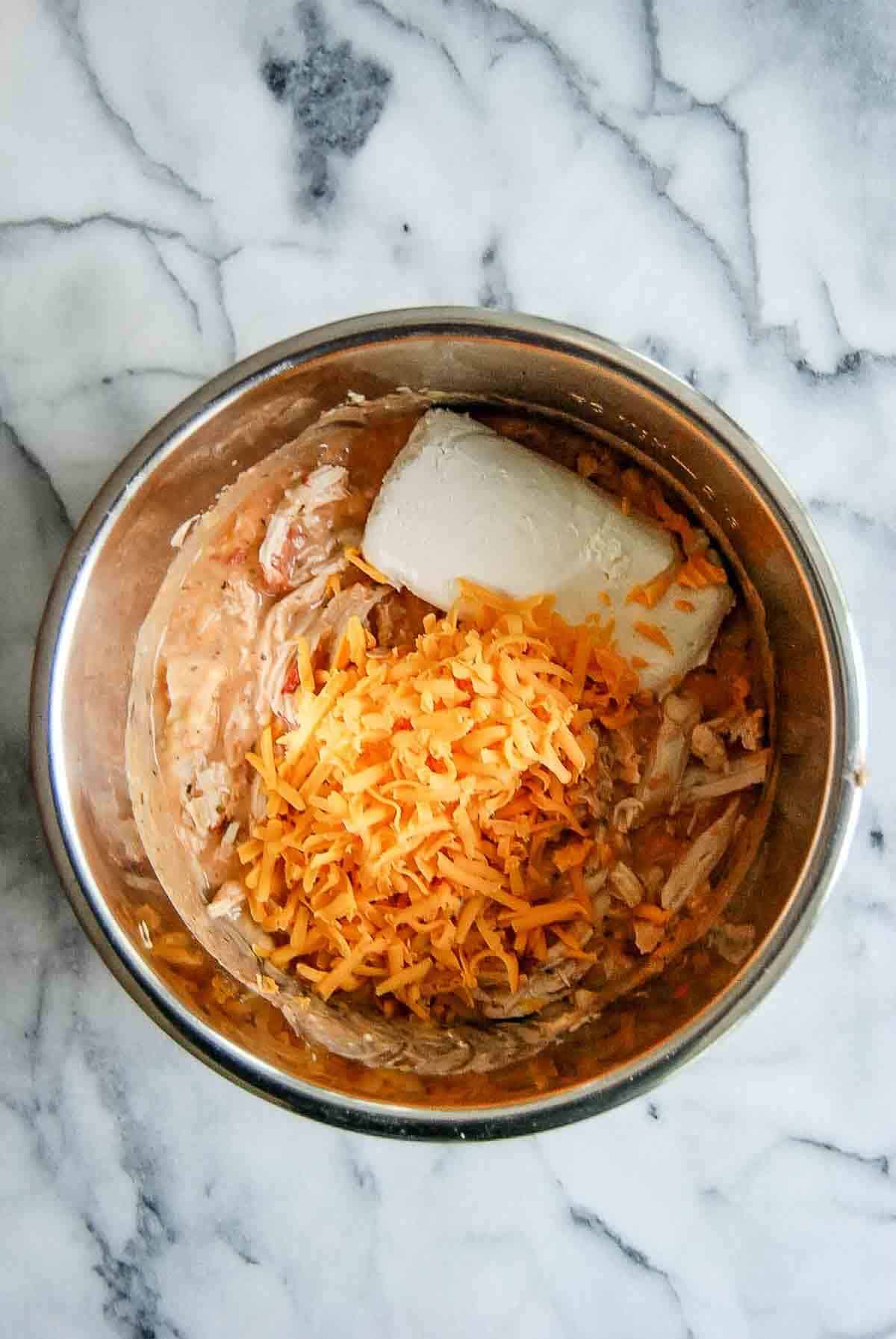 crockpot with chicken, sauce and cheeses.