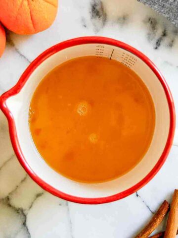 orange simple syrup in container on countertop.