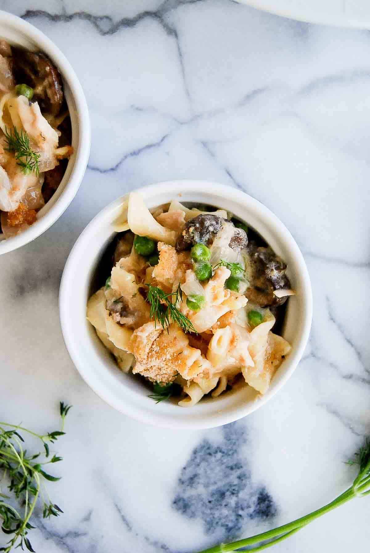 Close up of individual tuna noodle casserole serving topped with breadcrumbs and dill.