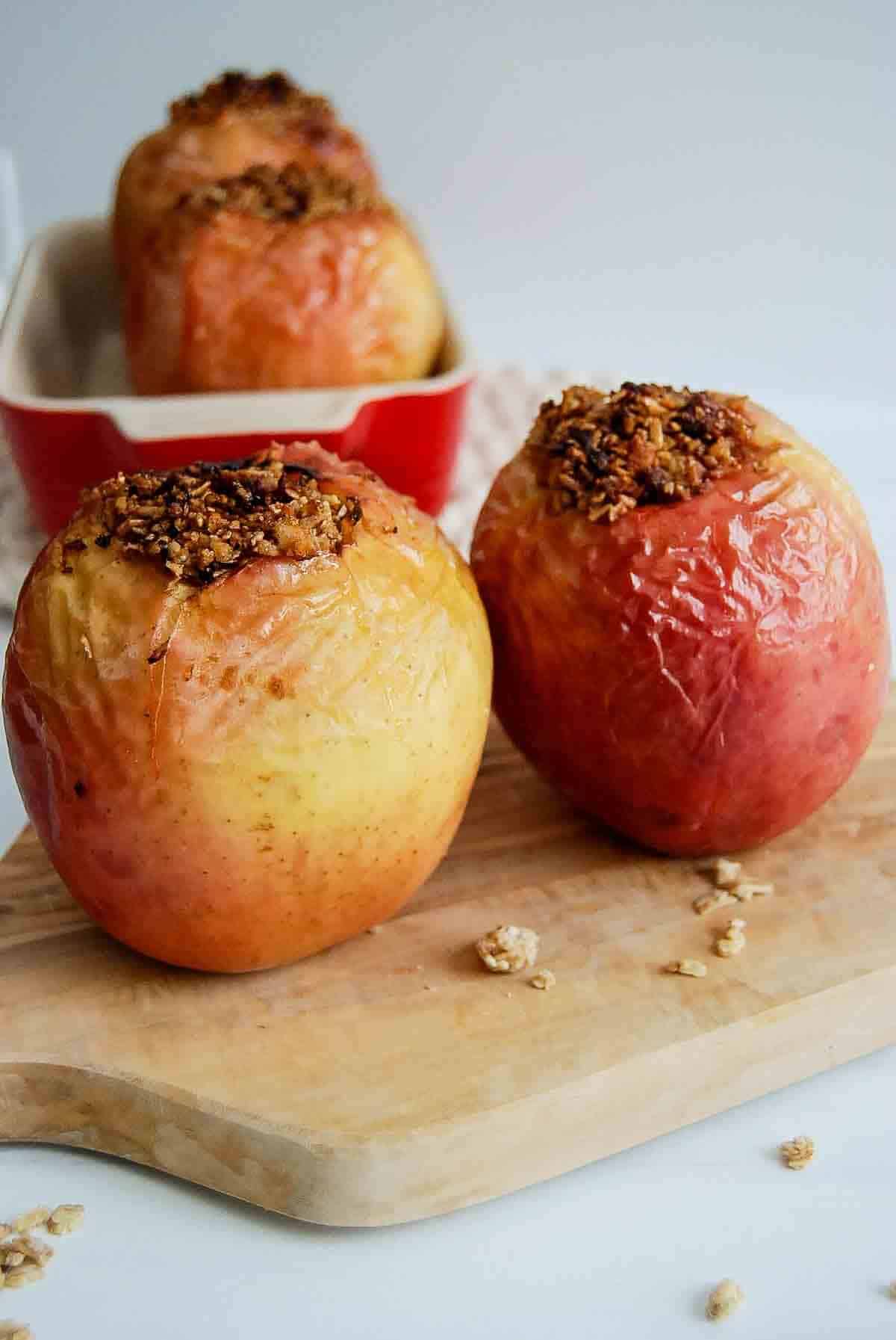 side view of 2 air fried apples on cutting board, stuffed with walnuts and oats.
