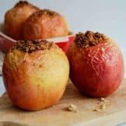 side view of 2 air fried apples on cutting board, stuffed with walnuts and oats.