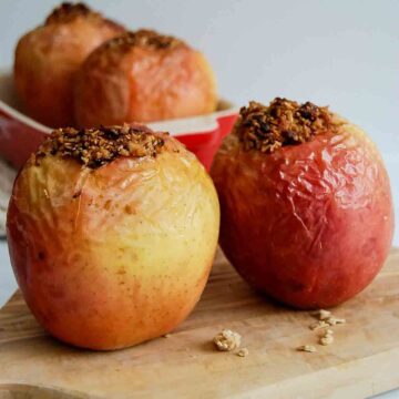 side view of 2 air fried apples on cutting board, stuffed with walnuts and oats.