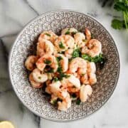 air fryer frozen shrimp with lemon garlic butter sauce in bowl.