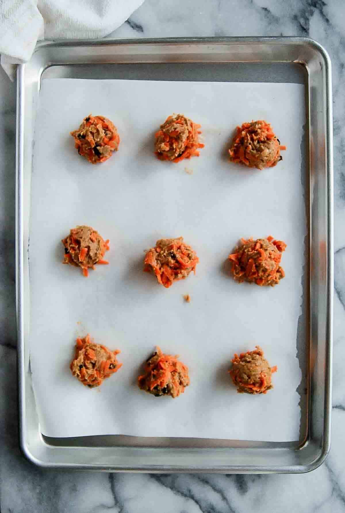 carrot cake cookie dough balls on baking tray lined with parchment paper.