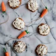 carrot cake cookies with coconut pecan and cream cheese icing on countertop.