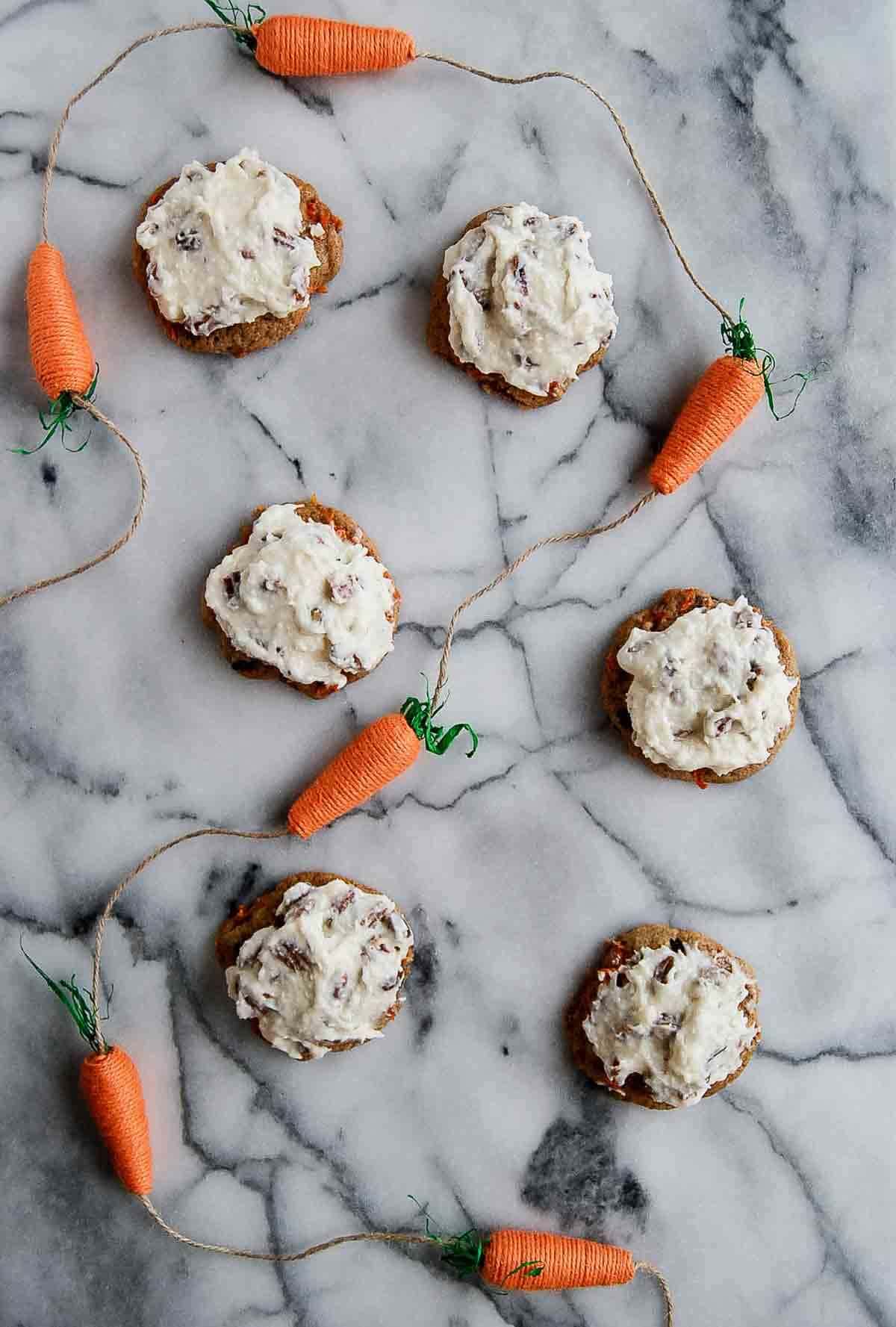 carrot cake cookies with coconut pecan and cream cheese icing on countertop.