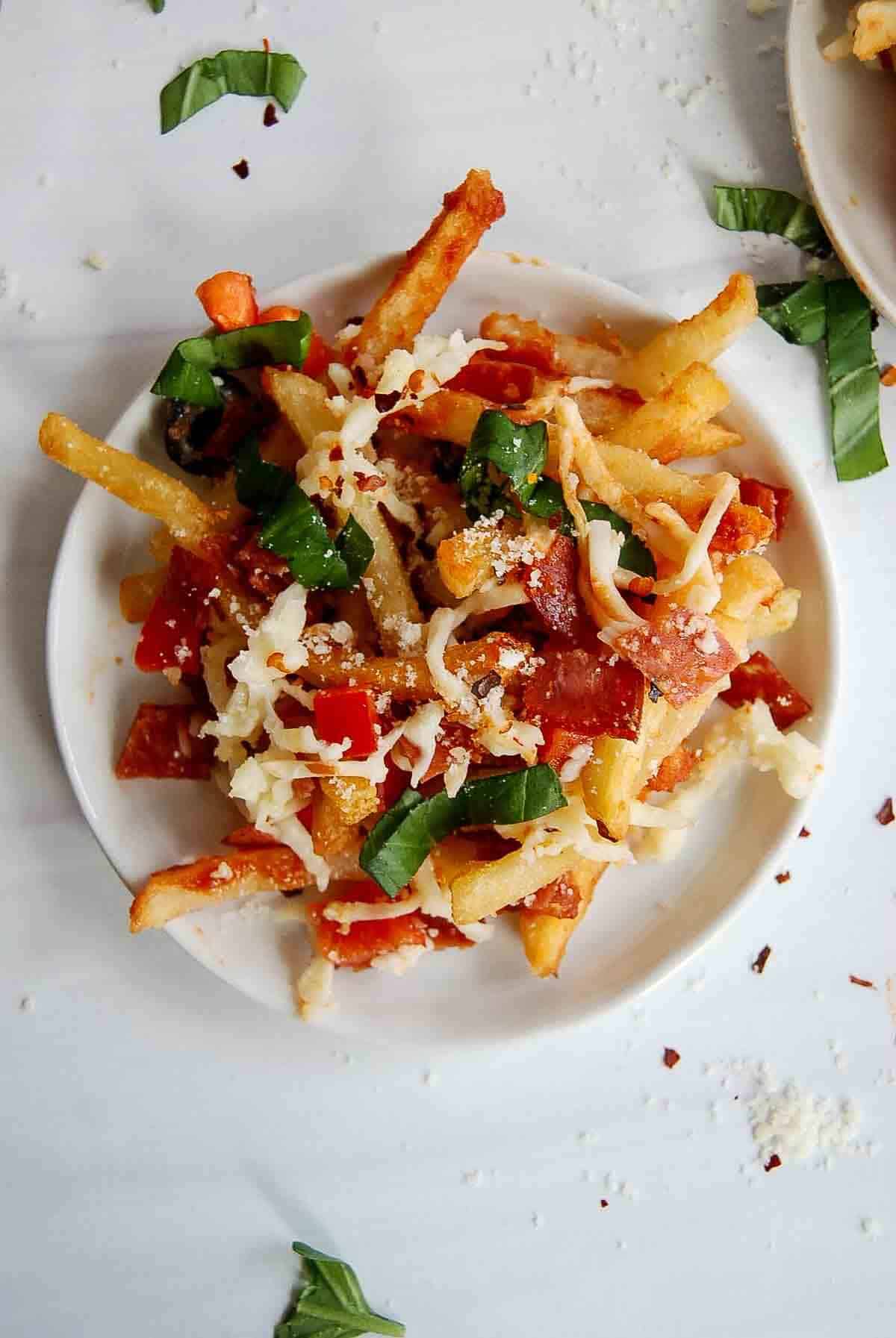 plate of pizza fries with pepperoni, basil, melted mozzarella, and red pepper.