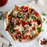 loaded pizza fries with pepperoni, red pepper, black olives, melted mozzarella and fresh basil.
