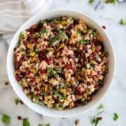 closeup view of pomegranate couscous salad with pistachio, lemon and mint.