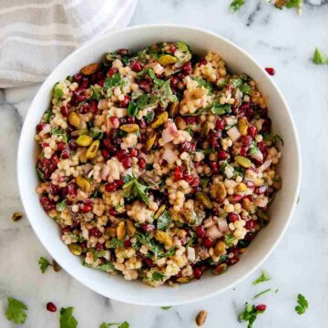 closeup view of pomegranate couscous salad with pistachio, lemon and mint.