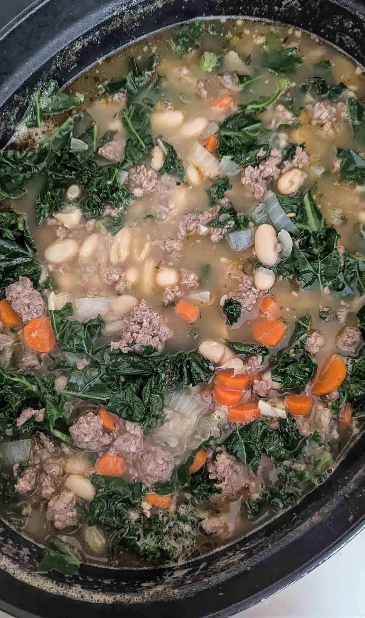 pot with sausage, kale and white bean soup on stove.