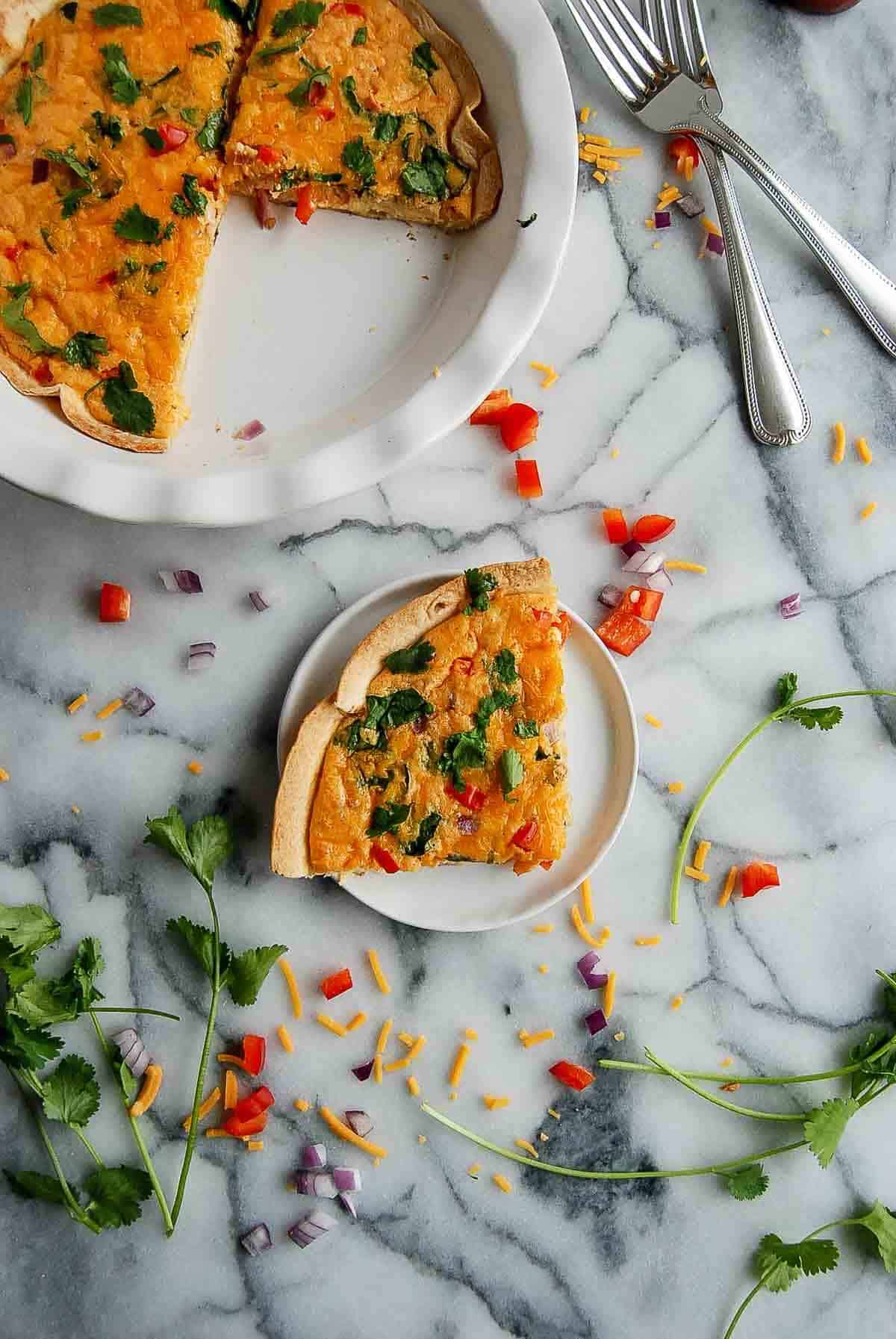 one piece of quiche on plate with full quiche on the side.