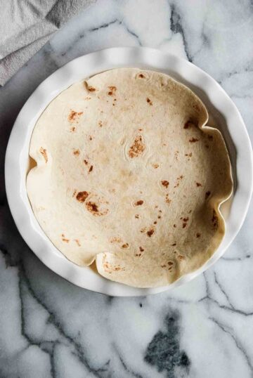 large tortilla in shallow pie pan on countetop.