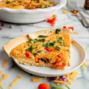 side view of tortilla quiche bake on plate with full quiche on the background.