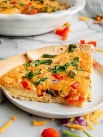 side view of tortilla quiche bake on plate with full quiche on the background.