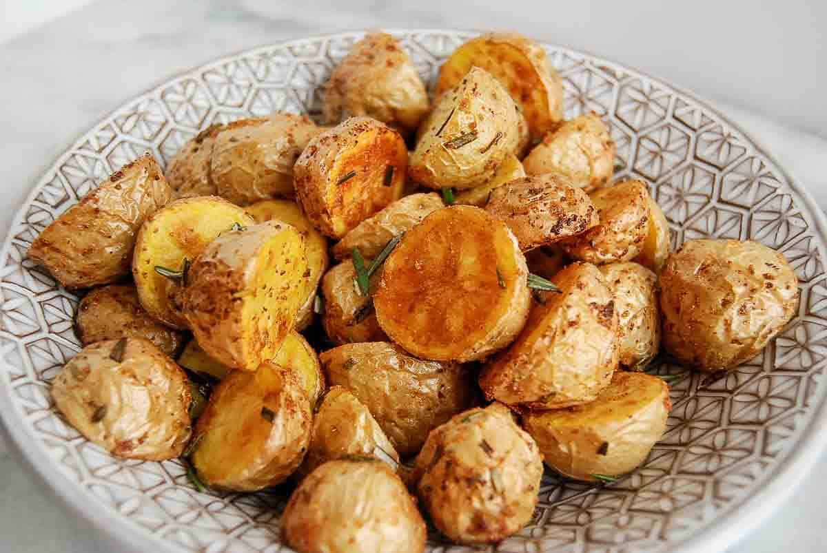 air fryere baby potatoes with garlic and rosemary in bowl on countertop.
