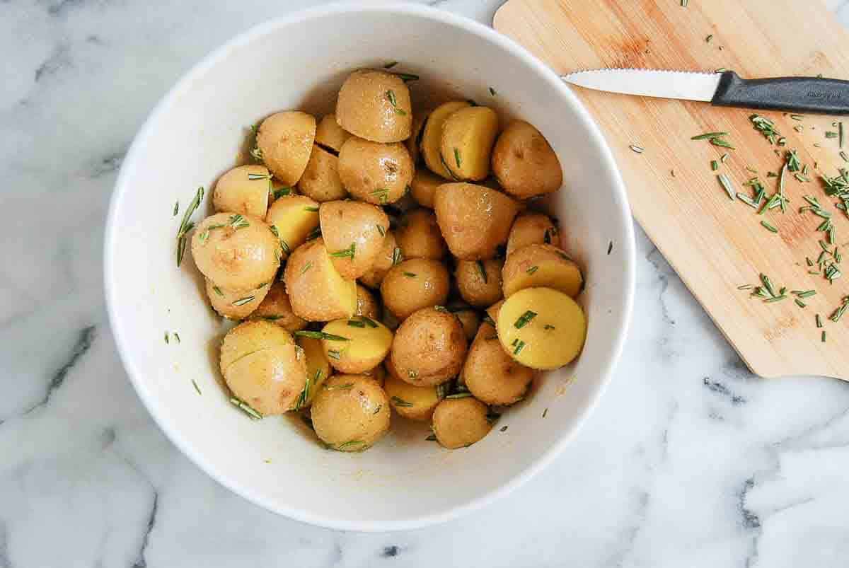 seasoned baby potatoes in bowl with chopped rosemary mixed in.